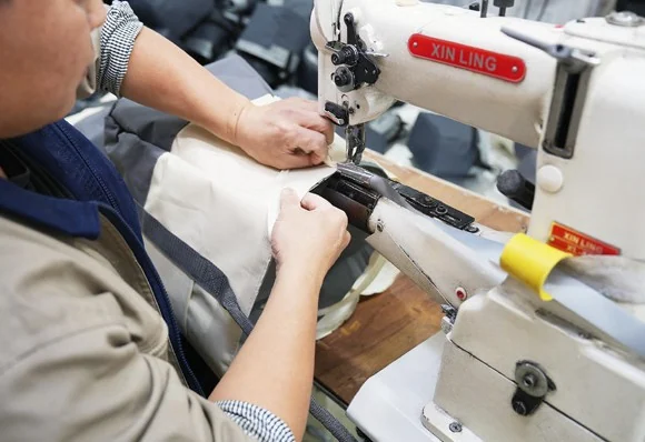 Close-up of layered fabric being stitched at a bag opening